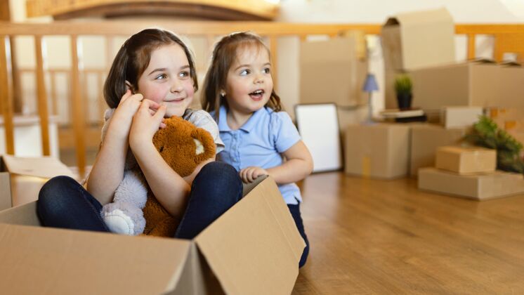 搬家带着盒子和玩具的笑脸孩子们室内家庭休闲