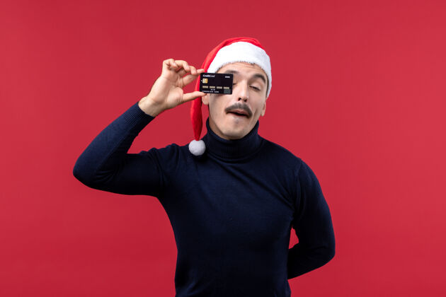 人正面图年轻男子手持红色背景的黑色银行卡歌手圣诞节红色