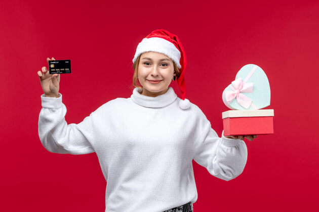 银行正面图：年轻女性 带着红色背景的银行卡和礼物卡片正面人