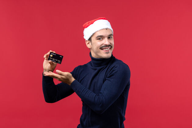 男人正面图红色背景上手持银行卡的年轻男性肖像圣诞节红色