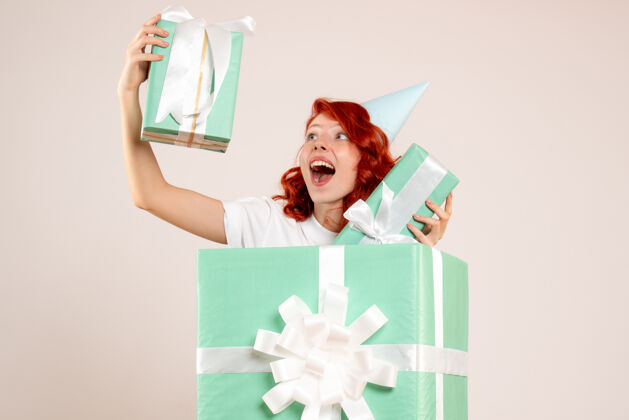 圣诞节正面图：在礼物里的年轻女子拿着白色背景上的其他礼物肖像礼物年轻女子