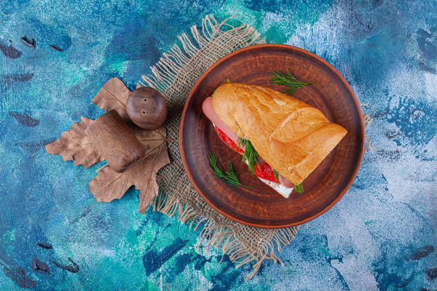 开胃菜在木板上夹三明治 在蓝色的粗麻布餐巾上美味烘焙美味