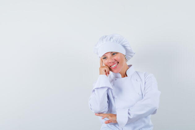 现代女厨师穿着白色制服站在思考的姿势 看起来很高兴女性时尚年轻