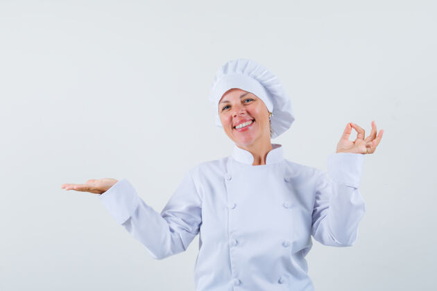 魅力女厨师展示赢家的姿态 同时把手掌摊开 穿着白色制服 看起来很高兴制服时尚厨师
