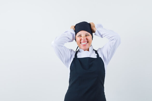 黑发穿着黑色厨师制服的金发女人 手举在头上 做鬼脸 优雅地微笑 看起来很漂亮化妆护理健康