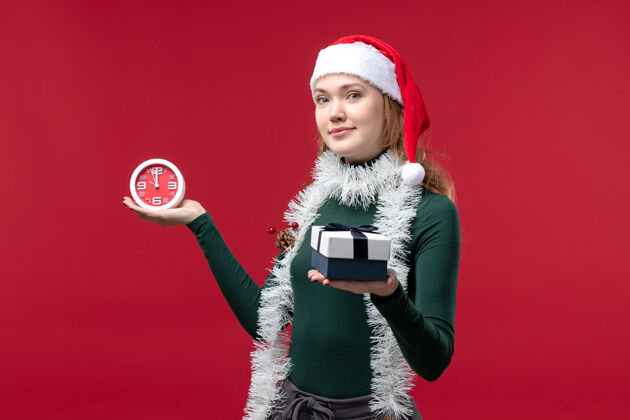 年轻女性正面图：年轻女性 红色背景上有带时钟的礼物服装圣诞节人