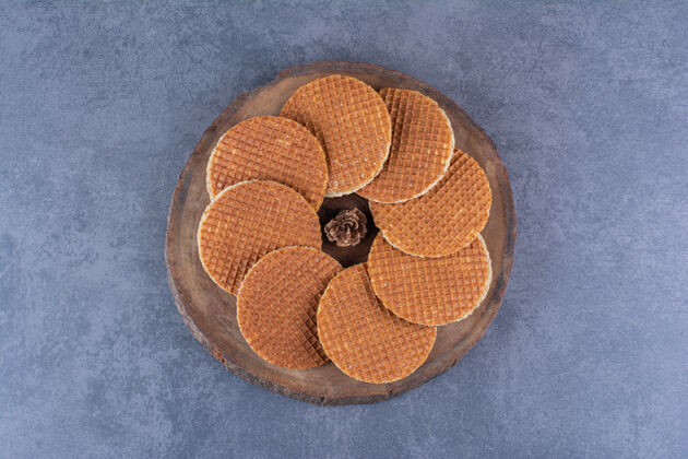 顶视图在石头上的一个木制盘子里隔离着松果的水晶华夫饼高质量的照片美味甜食甜点