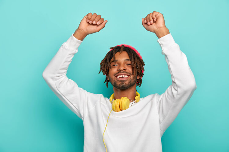 请精力充沛的家伙长着一头可怕的头发 举手投足 舞姿活泼 笑容灿烂 身穿白色套头衫 脖子上戴着耳机 在聚会上很受欢迎歌曲耳机快乐