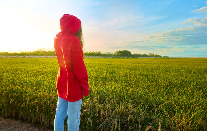 草地特写镜头一个年轻的红衣女子兴高采烈地站在一个阳光明媚的日子在绿地上田地女性女孩