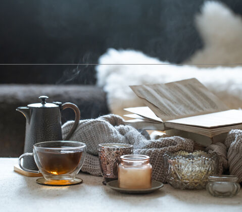 烟静物与一杯茶 一个茶壶 一本书和美丽的老式蜡烛烛台蜡烛家居装饰概念装饰蜡烛细节