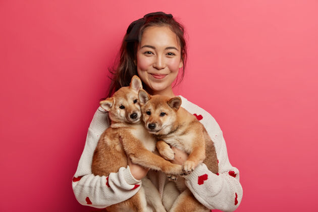 华丽快乐的韩国女狗主人展示她的家庭成员 站在两个可爱的血统小狗 买了狩猎石坝犬 花时间在家里高兴女性感情