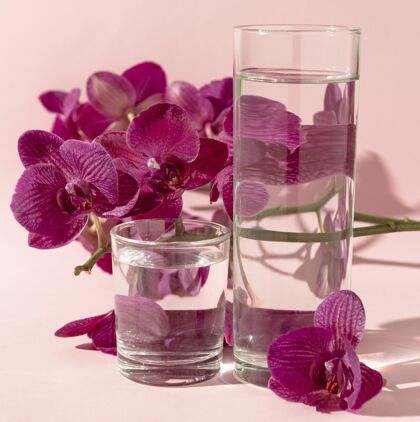 透明的玻璃杯子旁边放着水和花水的玻璃玻璃花