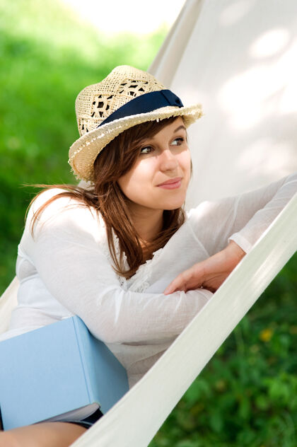 休息年轻女人拿着书在吊床上放松封面草地书封面