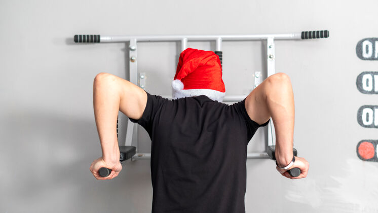 训练健身房高低杠上戴圣诞帽的男人后视图三头肌活动英俊