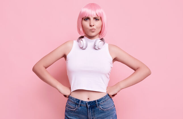 肖像美丽明亮的潮人女孩的肖像与粉红色的头发享受音乐在耳机上五颜六色香草娱乐耳机