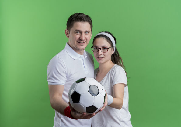 女人年轻的运动情侣男女一起拿着足球微笑着越过果岭抱着看球