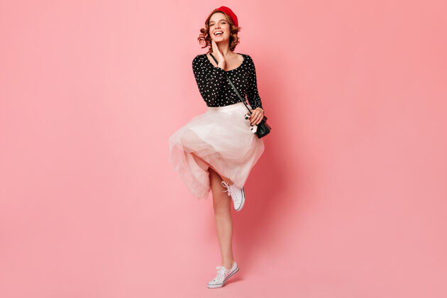 年轻人优雅的法国女孩 穿着白色胶鞋 在粉色背景上跳跃充满情感的漂亮女人 穿着裙子 微笑着跳舞粉色女性欢乐