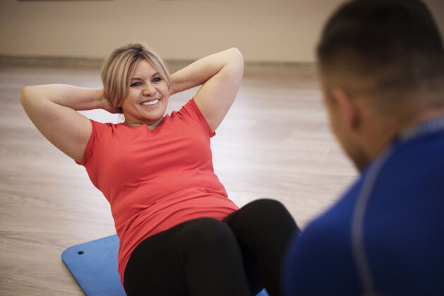 男人成熟的女人和教练一起锻炼健身房地板健康的生活方式