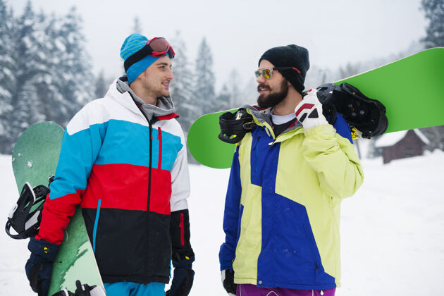 讨论两个家伙在寒假玩滑雪板山看向别处微笑