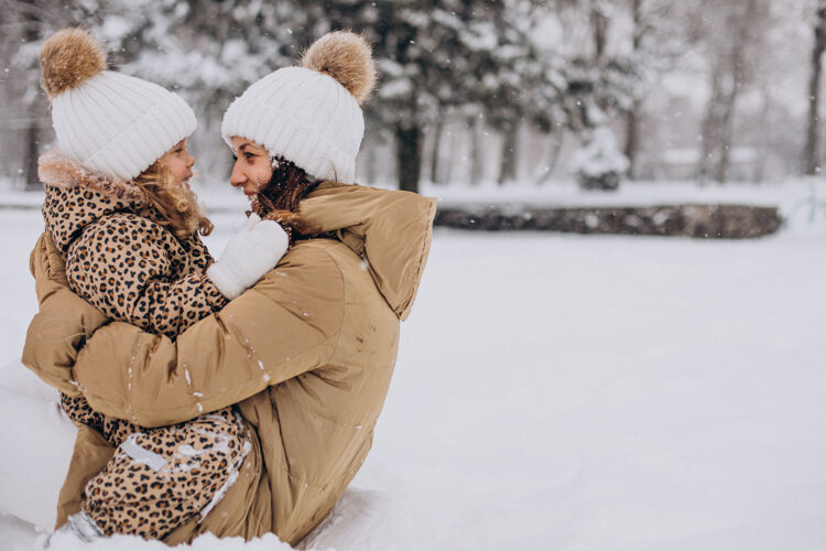 快乐妈妈和女儿在满是雪的公园里玩欢呼节日自然