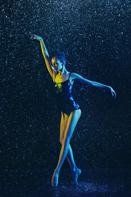 明亮年轻的女芭蕾舞演员在水滴和浪花下表演白种人模特在霓虹灯下跳舞迷人的女人芭蕾舞和当代舞蹈概念舞蹈女人平衡
