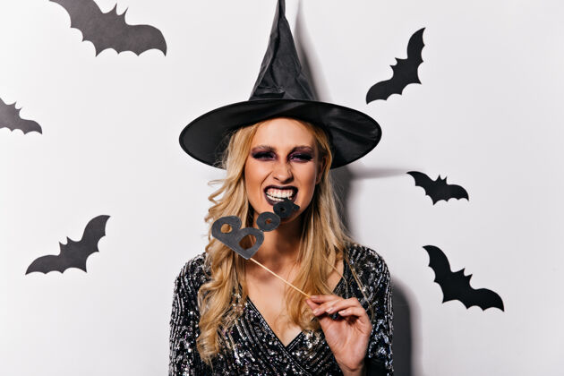 魔术师带着波浪发型的女巫庆祝万圣节戴着滑稽帽子的欣喜若狂的女吸血鬼与蝙蝠合影幻想庆典恐惧
