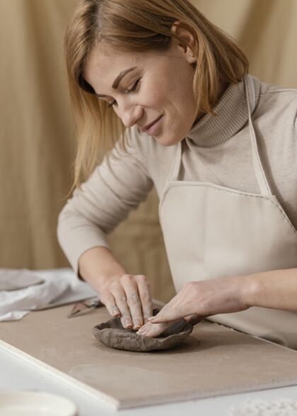 爱好特写笑脸做陶器的女人工匠女人室内