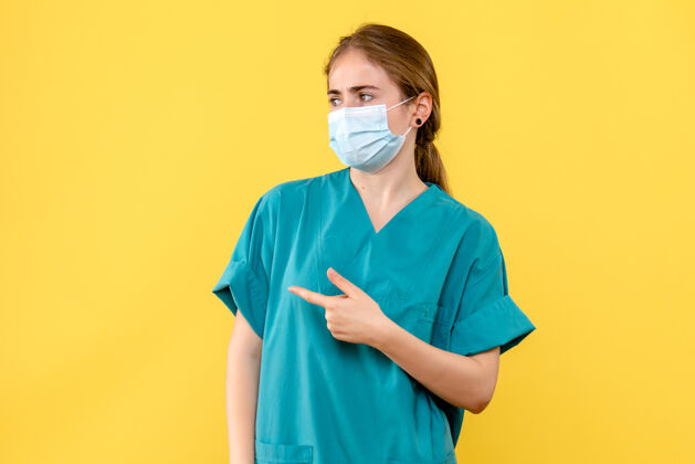 脸正面图黄色背景上戴着面罩的女医生医院病毒-大流行微笑实验室外套护士