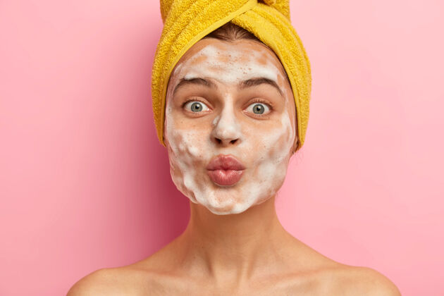 护理脸上有肥皂泡的美女 洗皮肤 裸体 头上戴裹着的毛巾泡沫肤色面部