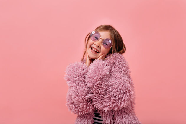 外套迷人的漂亮女孩 6岁 穿着紫罗兰色皮草 戴着圆眼镜 摆出快乐的姿势魅力小女孩时尚