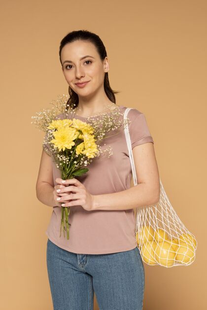 女人一个穿着休闲服的女人 手里拿着可重复使用的龟袋和花女性零浪费柠檬