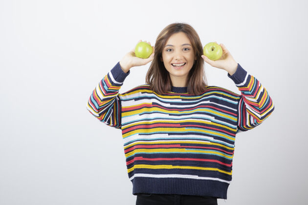 姿势一个年轻女子拿着两个新鲜的青苹果的画像模特女士新鲜