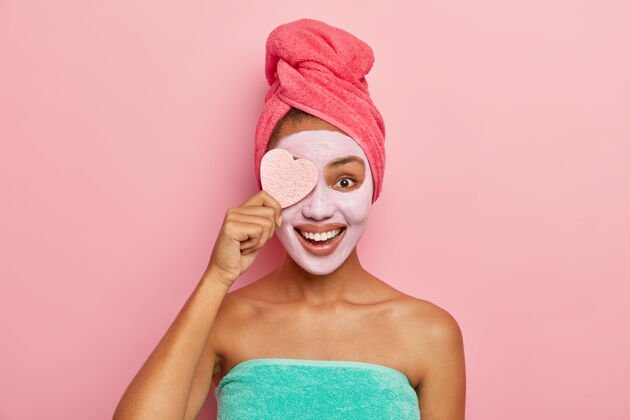 应用喜喜的女模特拿着化妆海绵 敷上适合自己皮肤的面膜 在浴室里做美容美容师高兴治疗