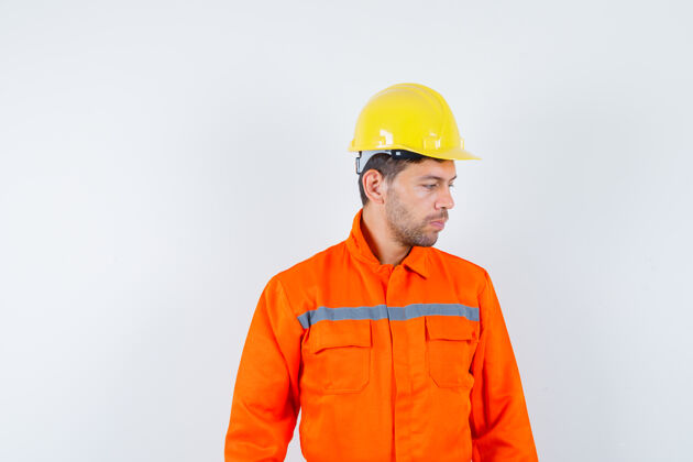 退休人员穿着制服的建筑工人 戴着头盔低头沉思着 正对着前方看团队制服计划