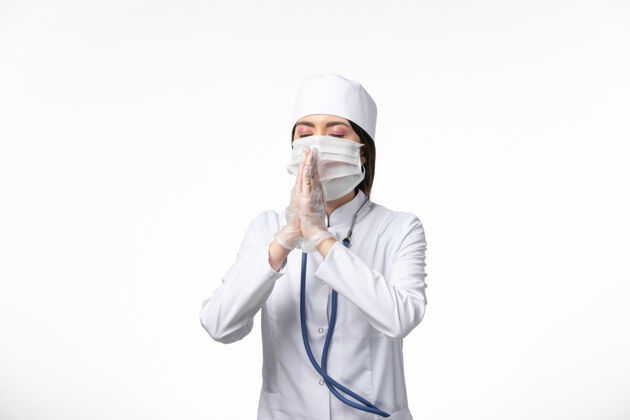 肖像正面图女医生穿着白色医疗服 戴着口罩 因白墙上有冠状病毒病药大流行套装到期医学
