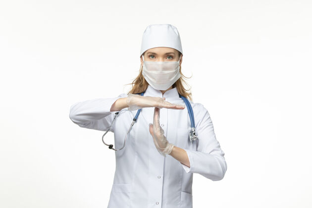 冠状病毒正面图女医生穿着医疗服戴着口罩和手套 因白墙上有冠状病毒大流行性冠状病毒医生女性疾病