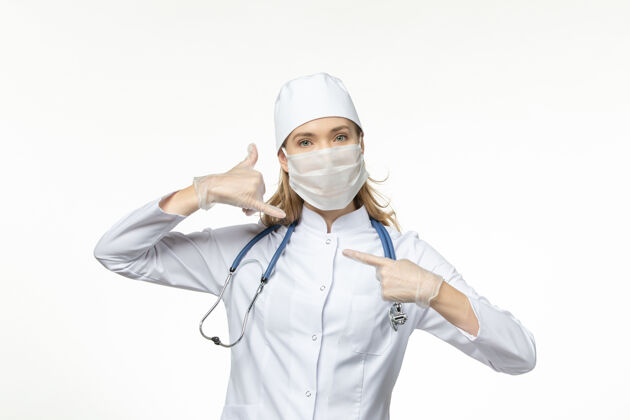 到期正面图女医生穿着医疗服戴着口罩和手套因冠状病毒在浅白的办公桌上大流行冠状病毒制服女性套装