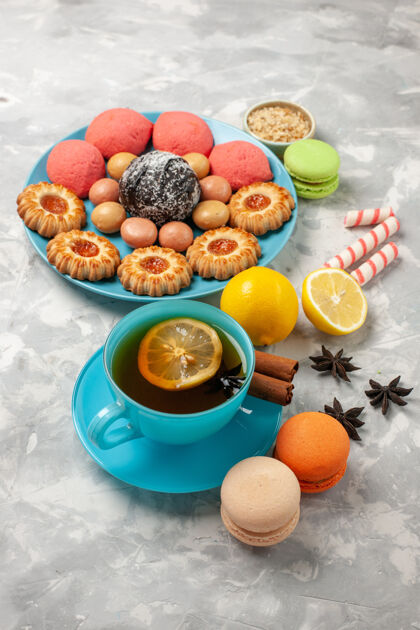 可食用的水果前视图一杯茶 配法国麦卡龙饼干和蛋糕 白色表面糖饼干甜蛋糕糖果饼干饮食茶蛋糕