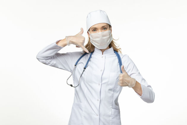 医疗前视女医生穿着医疗服戴着口罩和手套因冠状病毒在浅白的办公桌上大流行冠状病毒面罩疾病女性