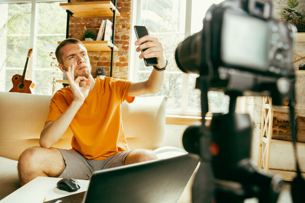 视频博客年轻的白人男性博主用专业相机录制视频评论智能手机在家男博客虚拟博客