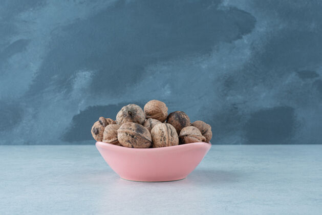 坚果在大理石背景上放满坚果的粉红色小盘高质量照片可口美味小