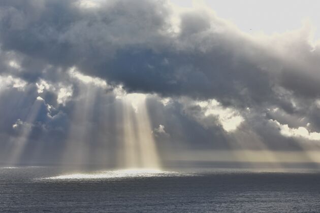 空气低角度拍摄阳光透过云层照射在美丽的海洋上多云海景光