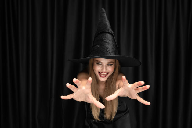 巫师年轻的金发女郎 戴着黑色帽子 穿着黑色背景的服装迷人 性感的女模特万圣节 黑色星期五 网络星期一 销售 秋天服装性感折扣