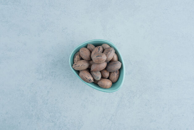 蓝色在大理石背景上放满坚果的蓝色小盘高质量照片可口干坚果