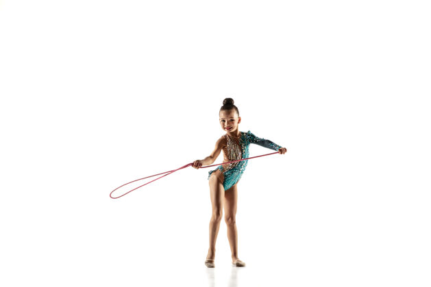 艺术家一个柔韧的小女孩被隔离在白色的墙上穿着鲜艳的紧身衣的艺术体操艺术家的小女模优雅的动作 动作和运动用跳绳做练习明亮优雅竞争