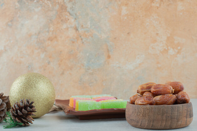 松果在大理石背景上放满干果和果酱的木制小碗高质量照片水果吃圣诞球