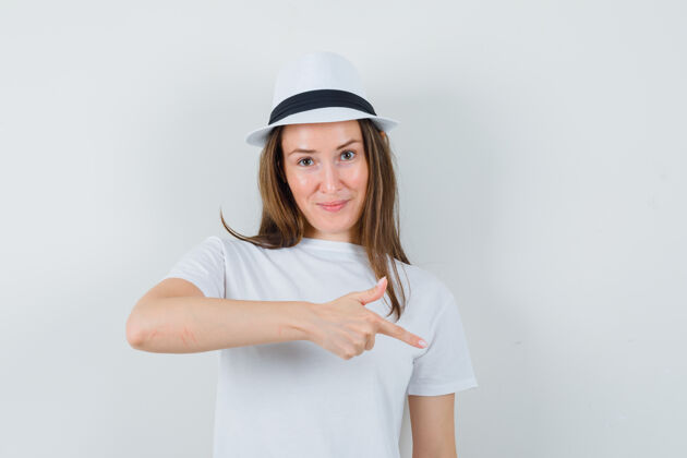 肖像穿着白色t恤的年轻女孩 帽子朝下 看起来很自信 正面视图帽子指向女人