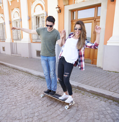 太阳镜溜冰的情侣在城里玩得很开心异性情侣微笑阳光