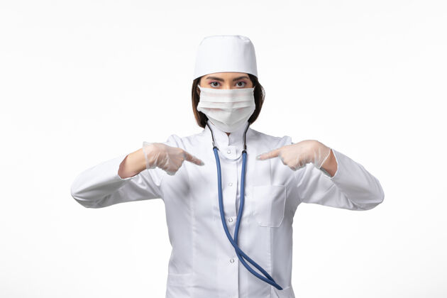 医生正面图女医生穿着白色医疗服 戴着口罩 由于白色办公桌上有冠状病毒疾病大流行病毒covid-女性桌子疾病