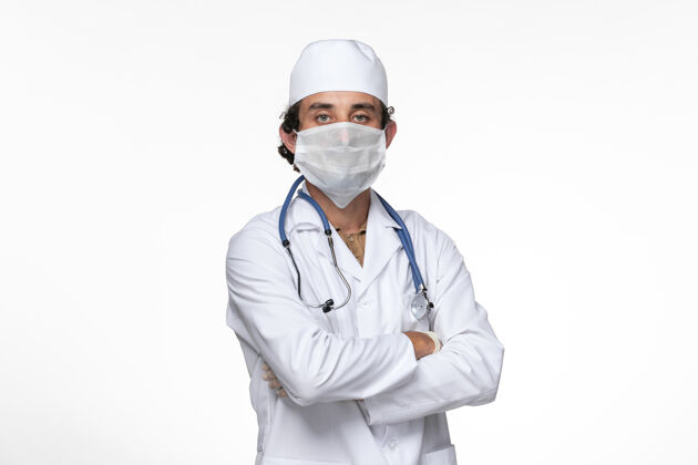 冠状病毒防护正面图：男医生穿着医疗服 戴着口罩 以防柯维德-白墙病毒疾病-健康柯维德-大流行病毒冠状病毒预防大流行